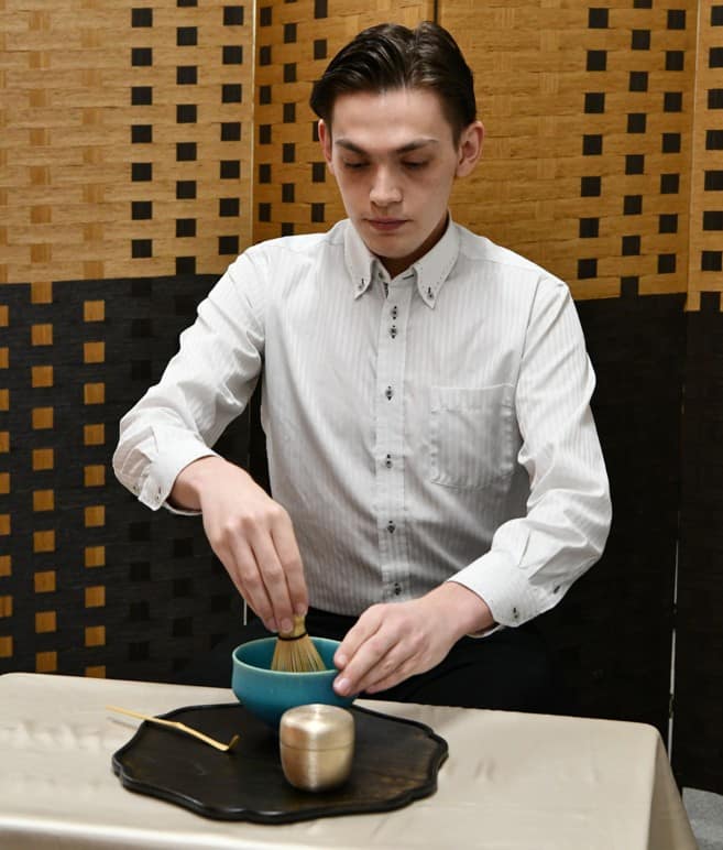 オフィスのテーブルで抹茶を点てる男性社員