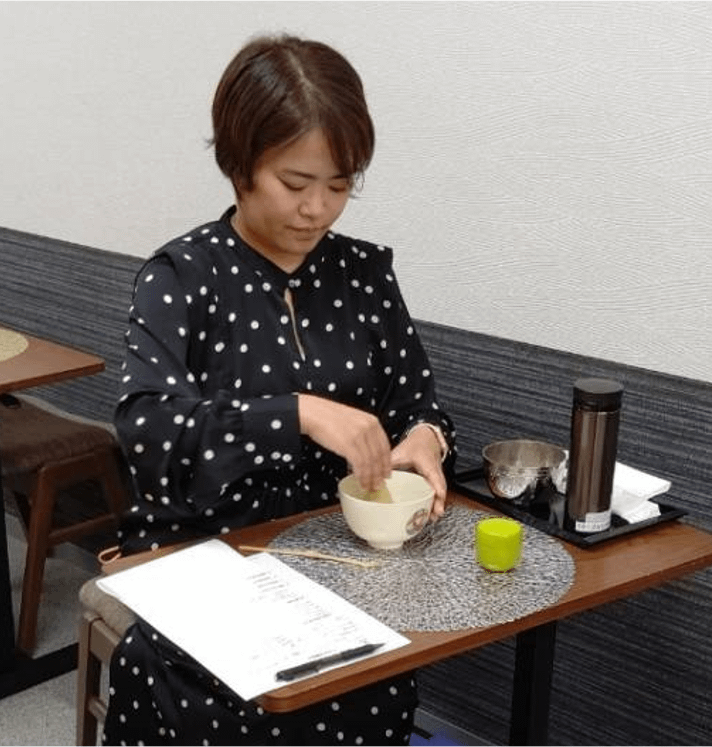 テーブルで抹茶を点てる女性
